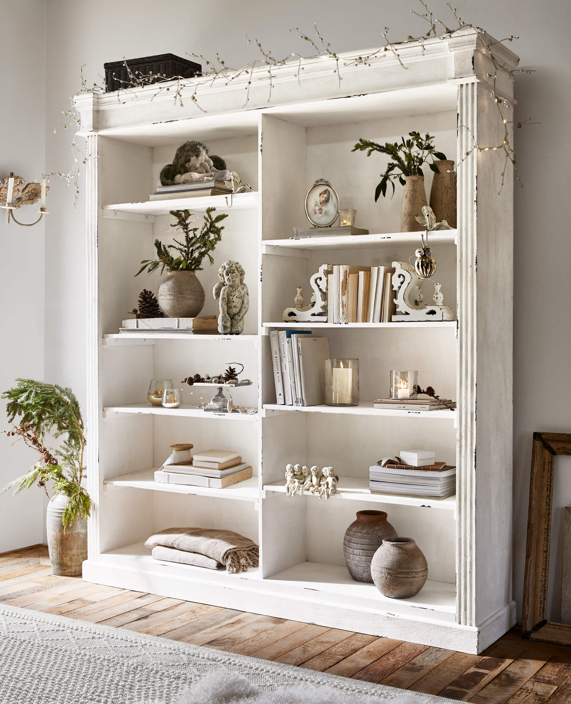 Weiße Holzregal mit Vintage-Dekorationen und Büchern auf hellem Holzboden