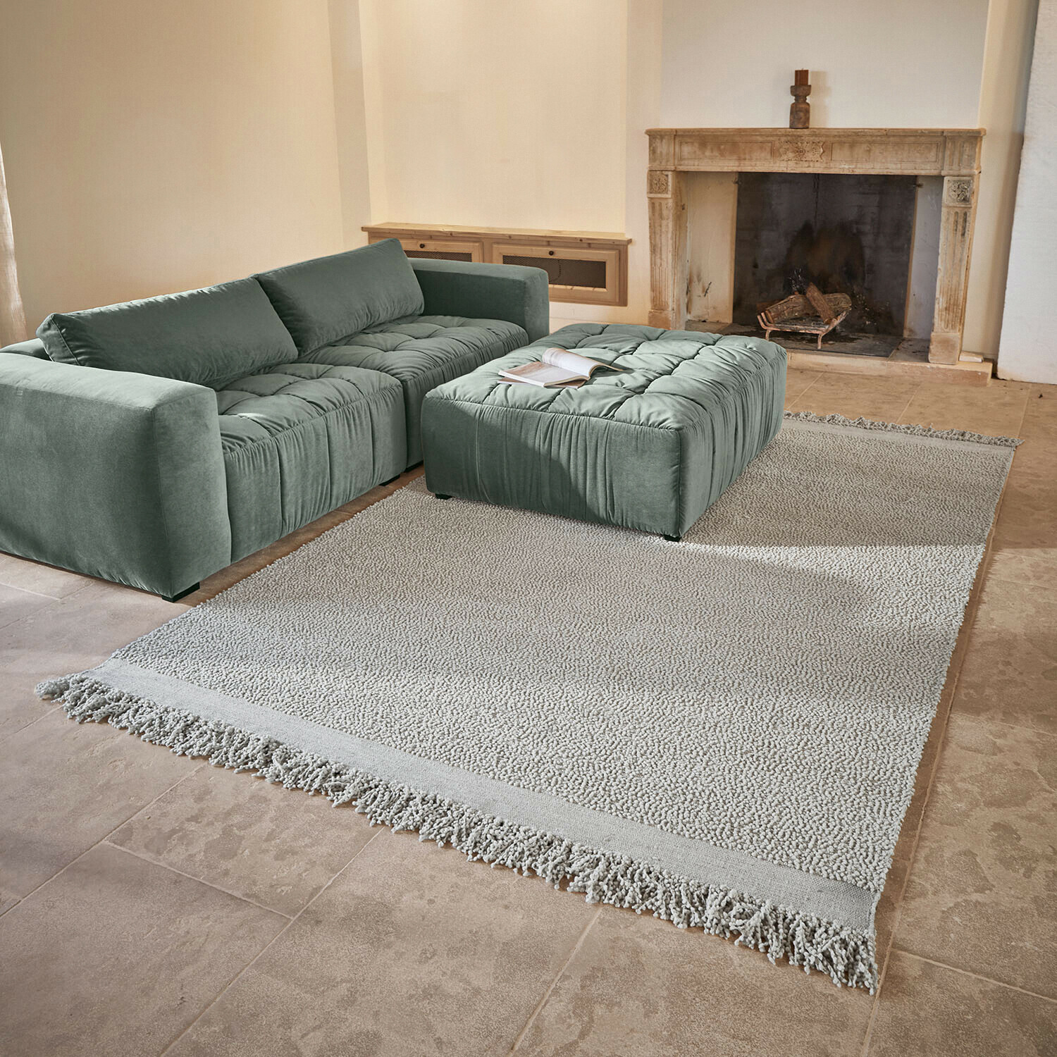 Teppich Linnet Mintgrünes Sofa und Polster aus weichem Stoff auf hellem Teppich mit Fransen im Wohnzimmer mit Kamin