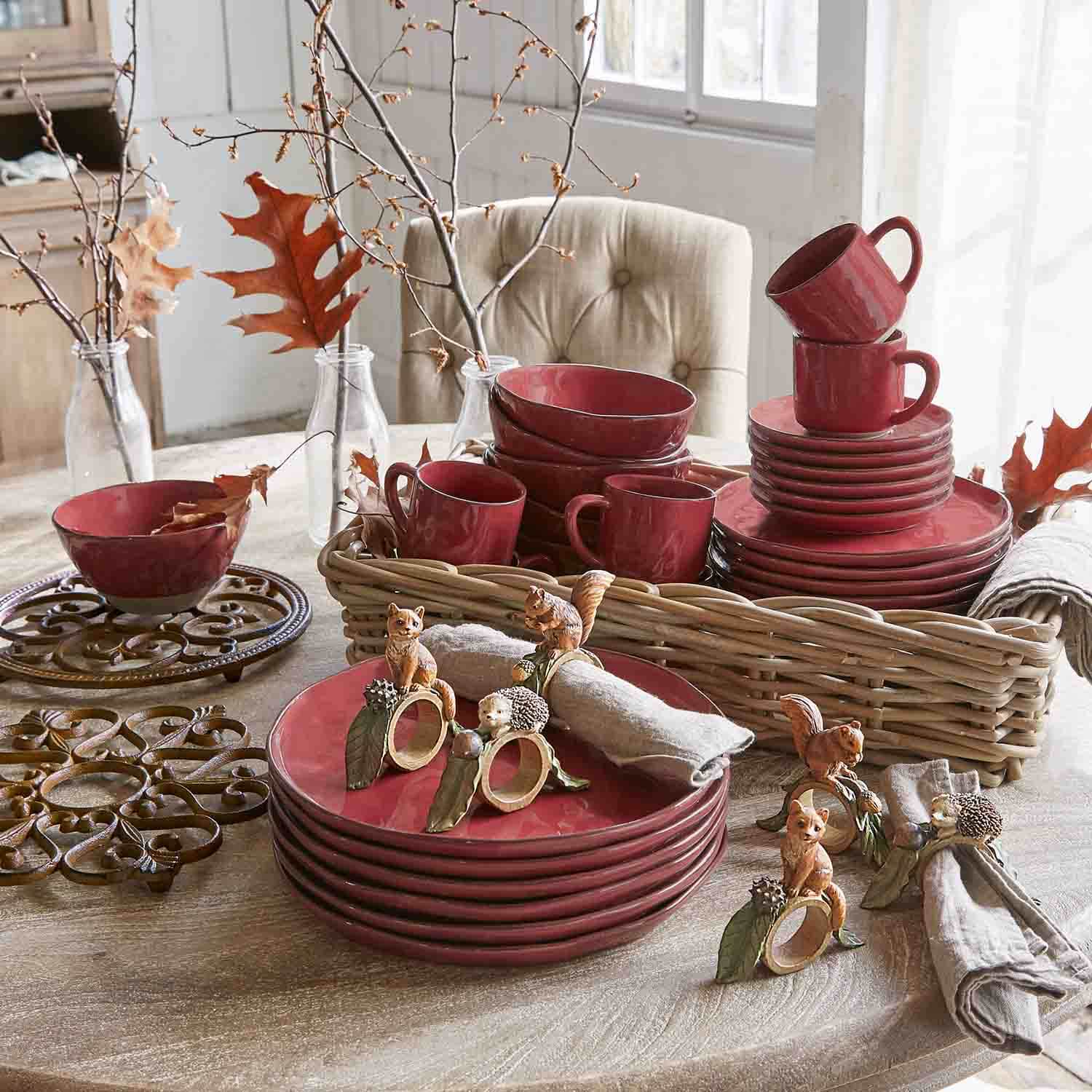 Rotes Keramik-Geschirrset mit Tassen und Tellern auf Holztisch mit herbstlicher Dekoration