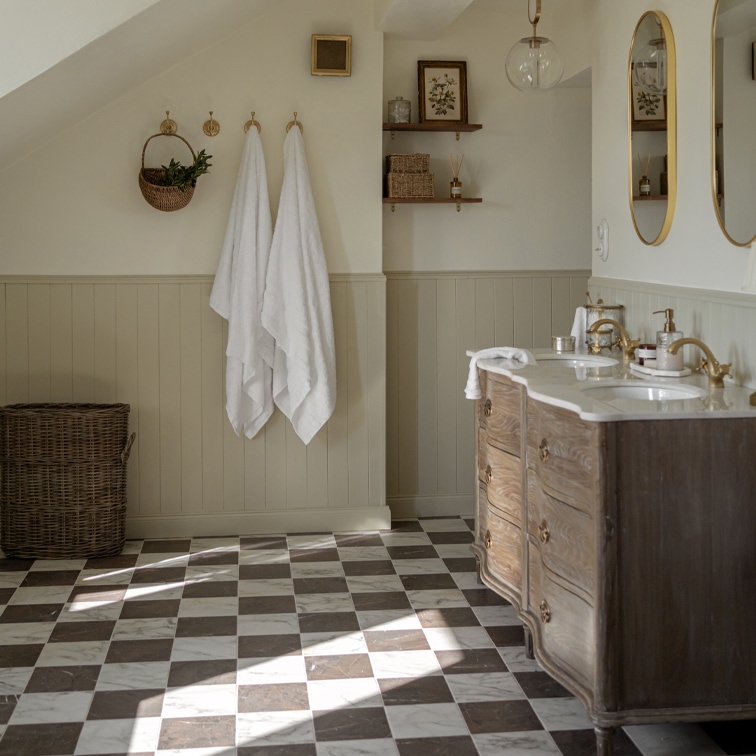 Badezimmer mit kariertem Marmorboden, Holzkommode und weißen Handtüchern an Haken