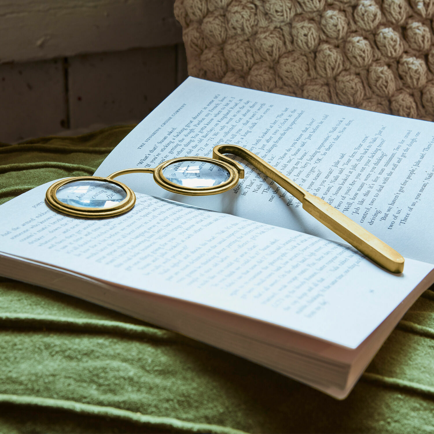 Lupe Robert Goldene Lesebrille mit runden Gläsern auf offenem Buch auf grünem Stoff