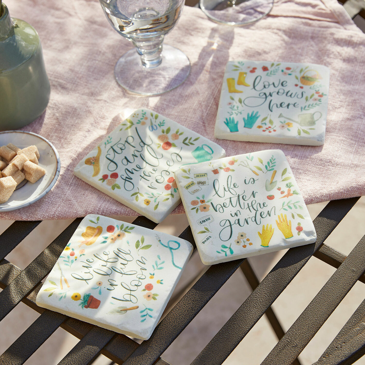 Untersetzer 4er Set Happy Set aus vier Keramikuntersetzern mit bunten Gartendesigns und Schriftzügen auf hellem Hintergrund