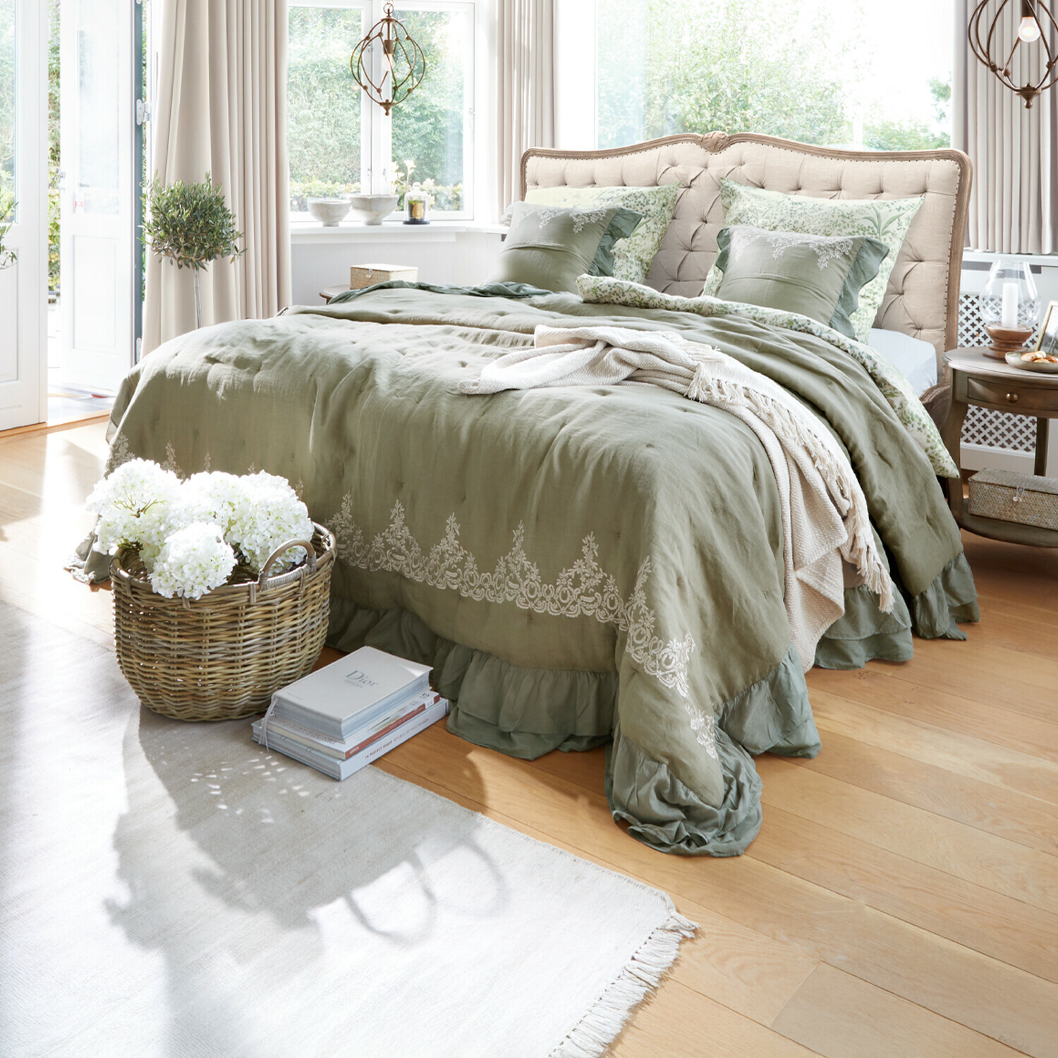 Schlafzimmer mit beige gepolstertem Kopfteil und grüner Leinenbettwäsche mit Stickerei