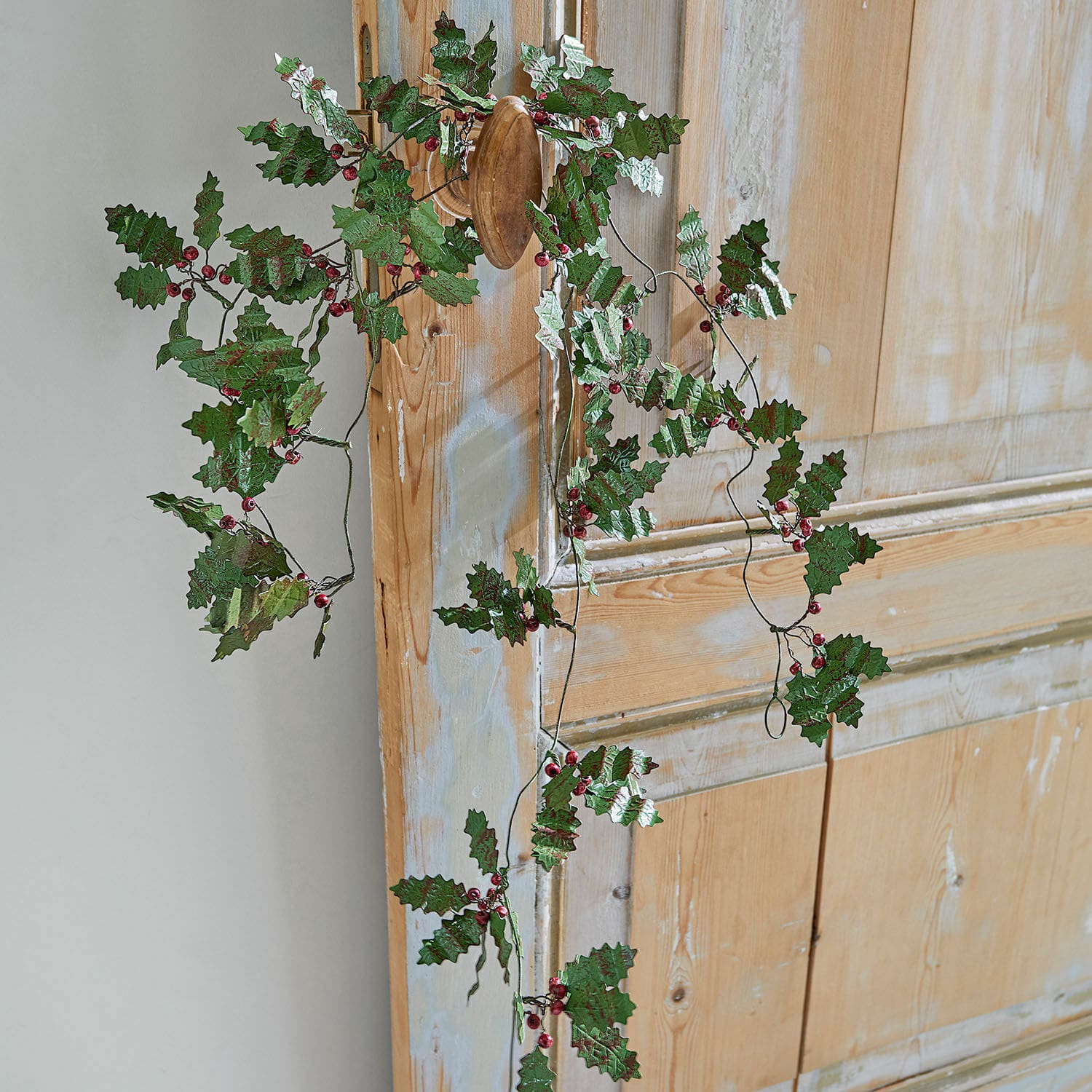 Girlande Fleur Dekorativer Kranz mit grünen Blättern und roten Beeren an Holztür, festliche Weihnachtsdekoration