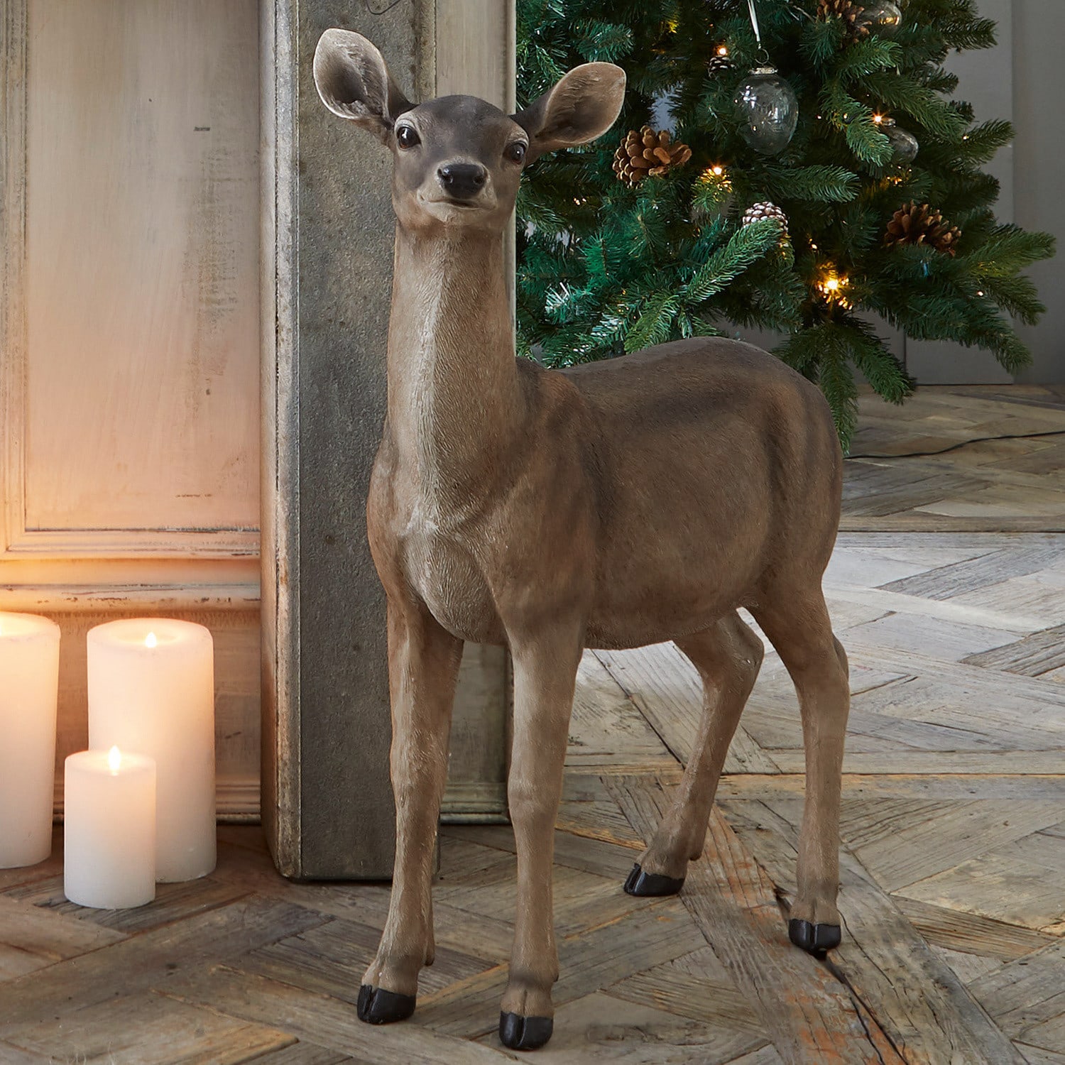 Reh Ruud Braune dekorative Hirschfigur vor beleuchtetem Weihnachtsbaum und Kerzen