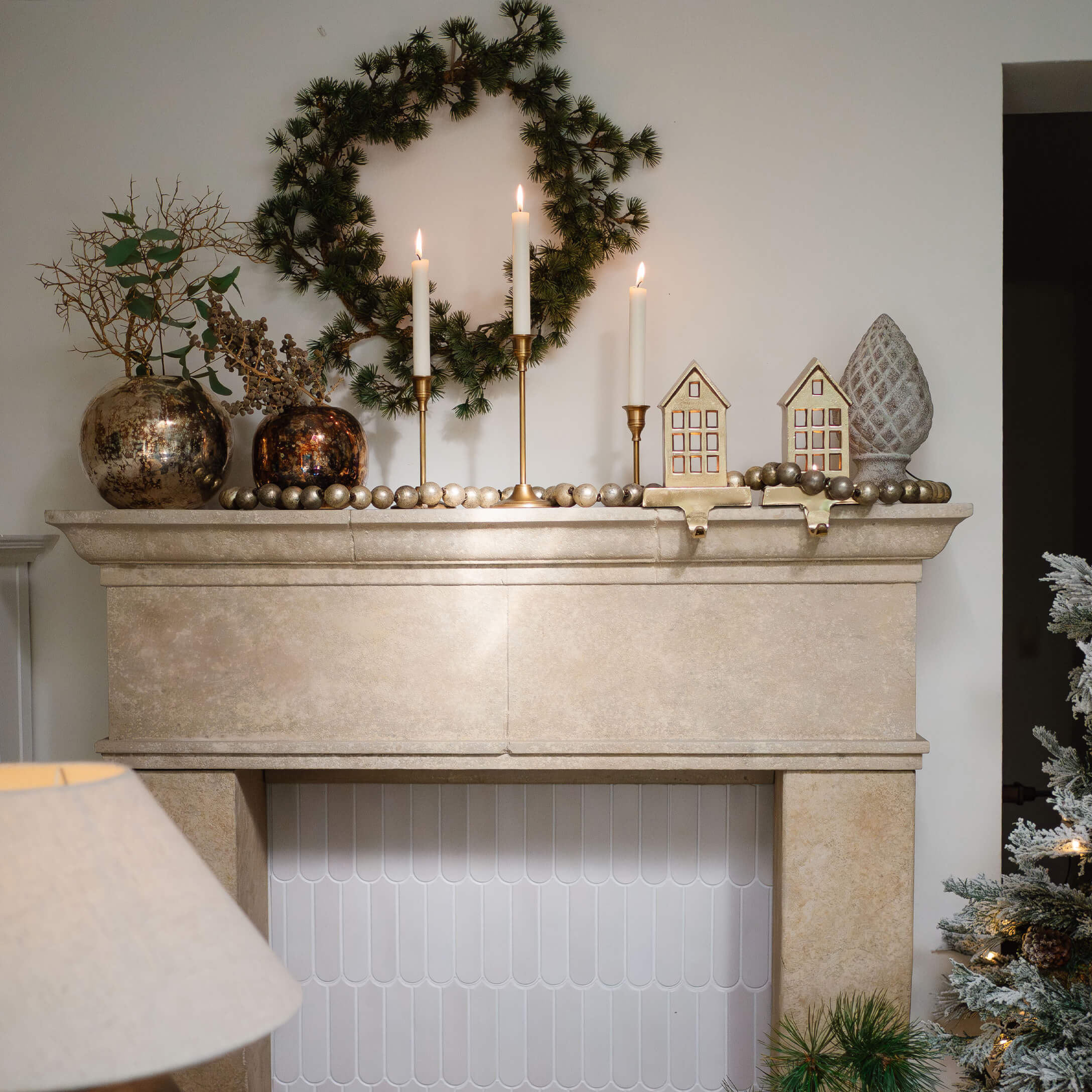 Beiger Steinkamin mit grünem Kranz, goldenen Kerzenhaltern und festlicher Weihnachtsdekoration
