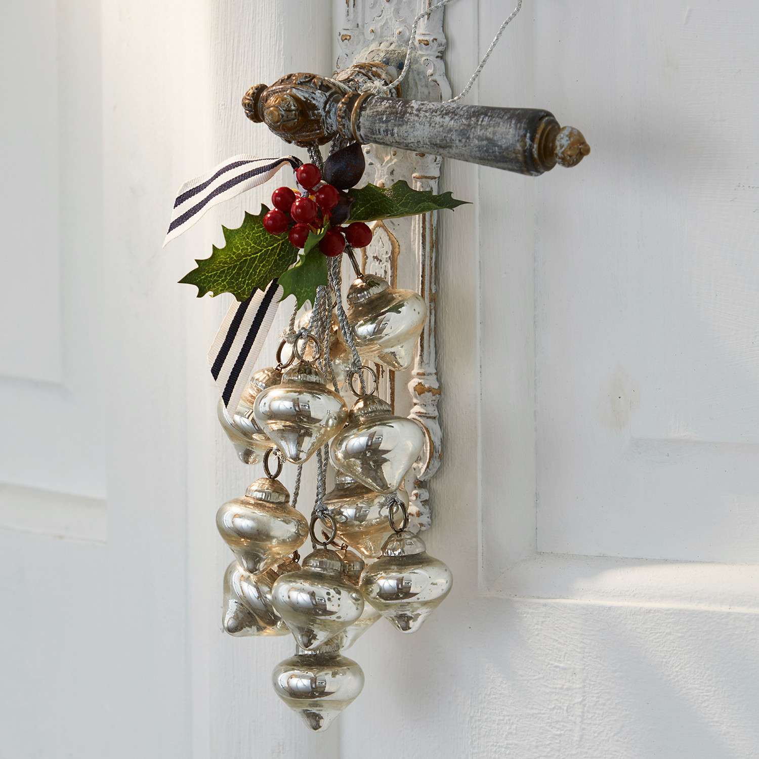 Weihnachtsschmuck Sassey Weihnachtsschmuck aus silbernem Glas mit roten Beeren an weißer Tür hängend