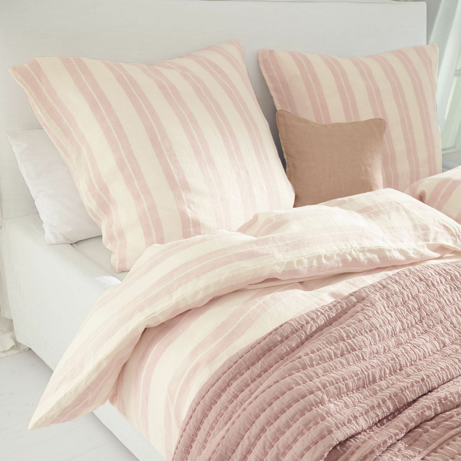 Bettwäsche Dordogne Bettwäsche aus Baumwolle in rosa-creme Streifen mit weicher rosa Decke auf hellem Bett