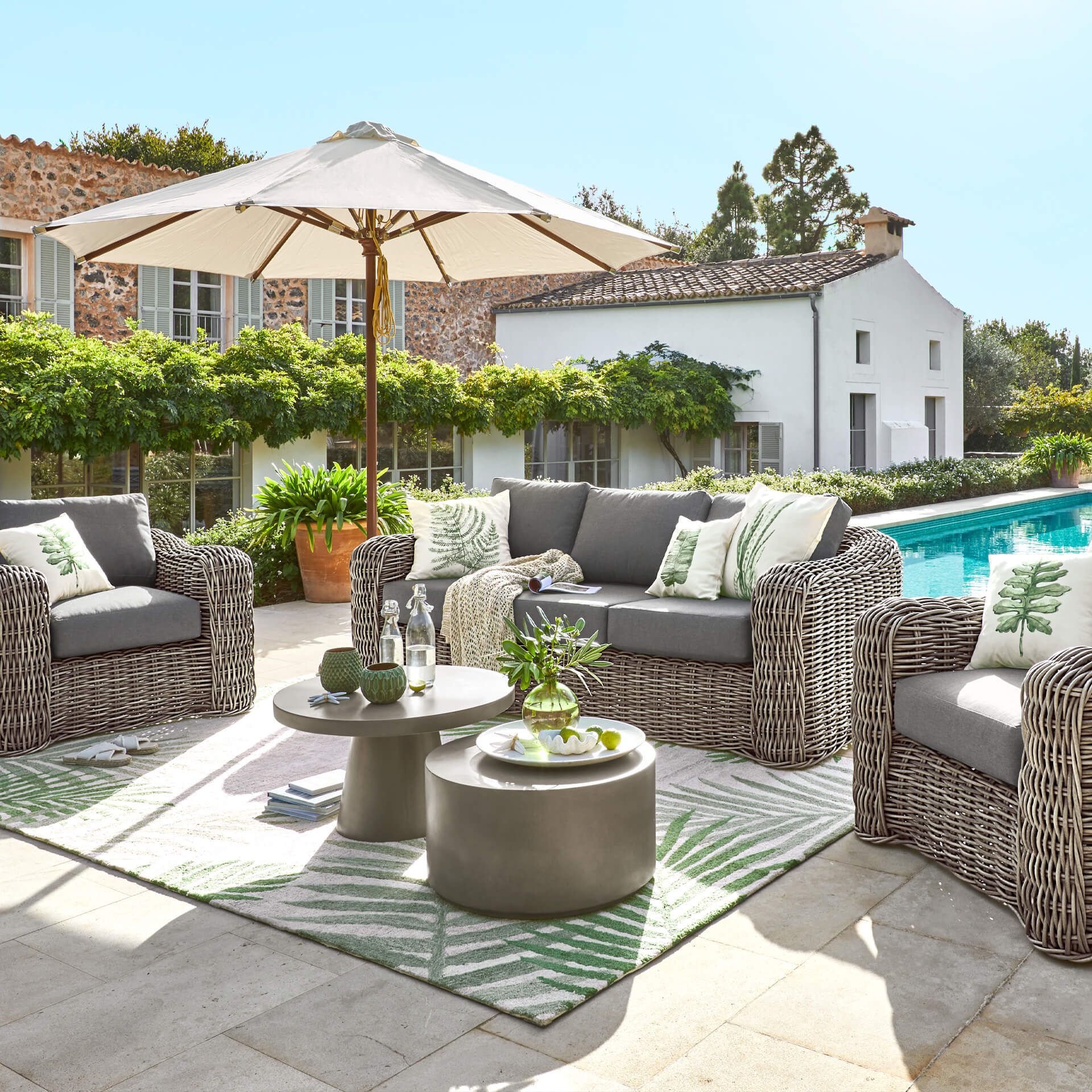 Gartenmöbel-Set aus grauem Technorattan mit Kissen und Sonnenschirm am Pool