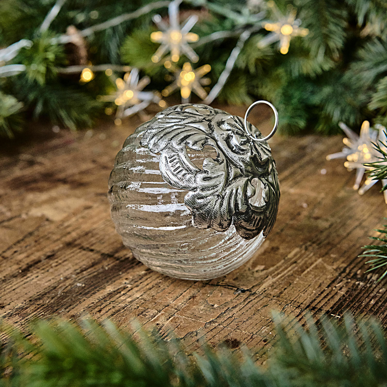 Weihnachtskugel Zoriline Glaskugel mit silberner Metallverzierung auf Holztisch mit grünen Tannenzweigen als Weihnachtsdeko
