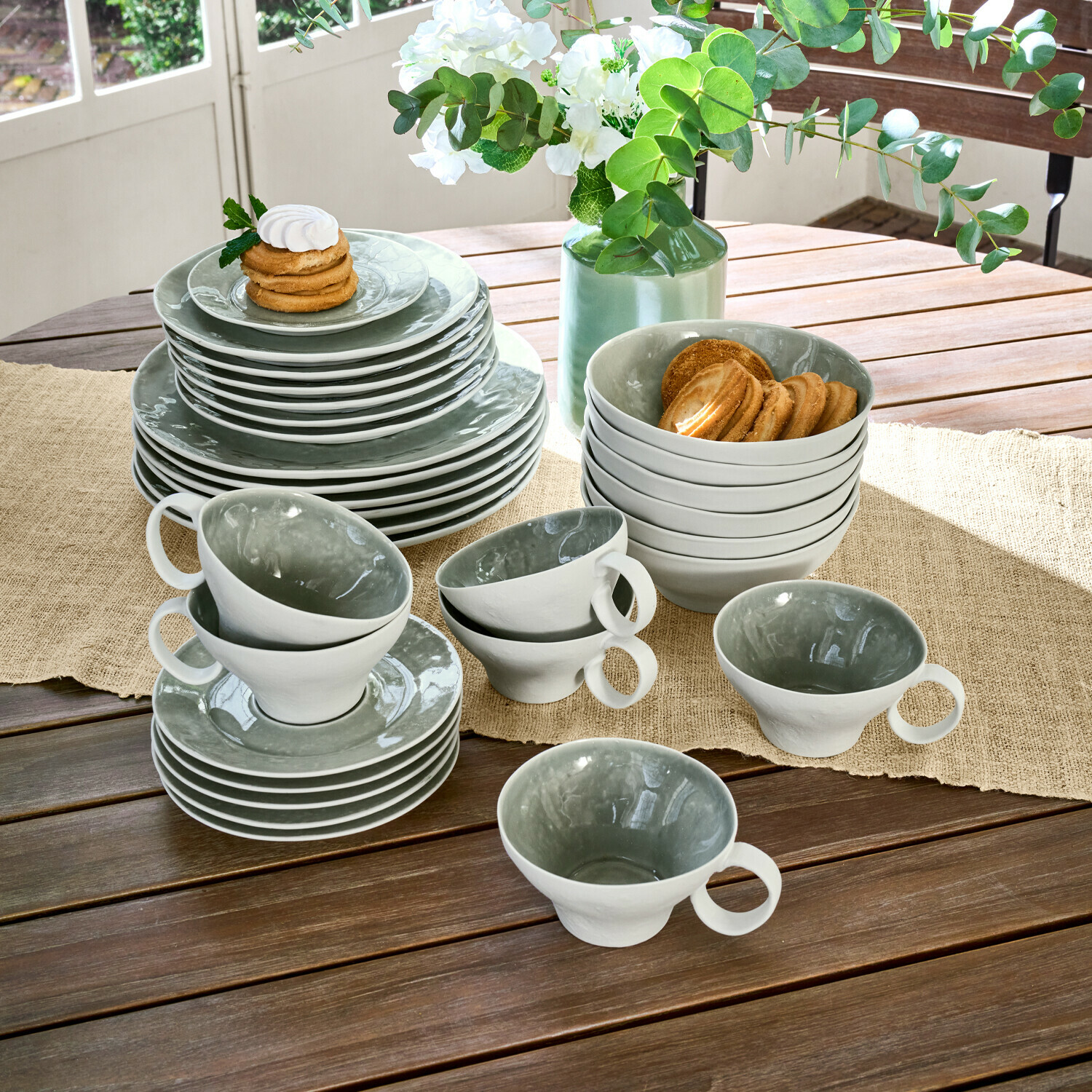 Geschirr 30er Set Braganza Graues und weißes Keramikgeschirr-Set auf Holztisch mit Keksen und Blumendekoration