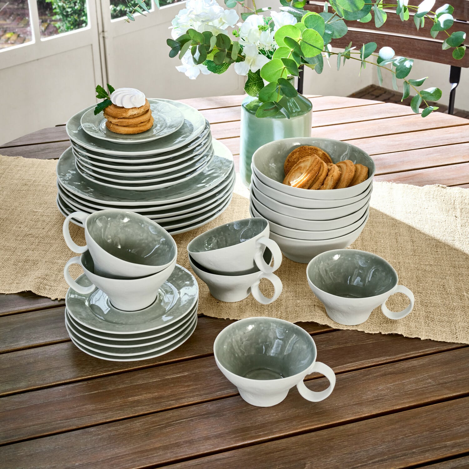 Geschirr 30er Set Braganza Graues und weißes Keramikgeschirr-Set auf Holztisch mit Keksen und Blumendekoration