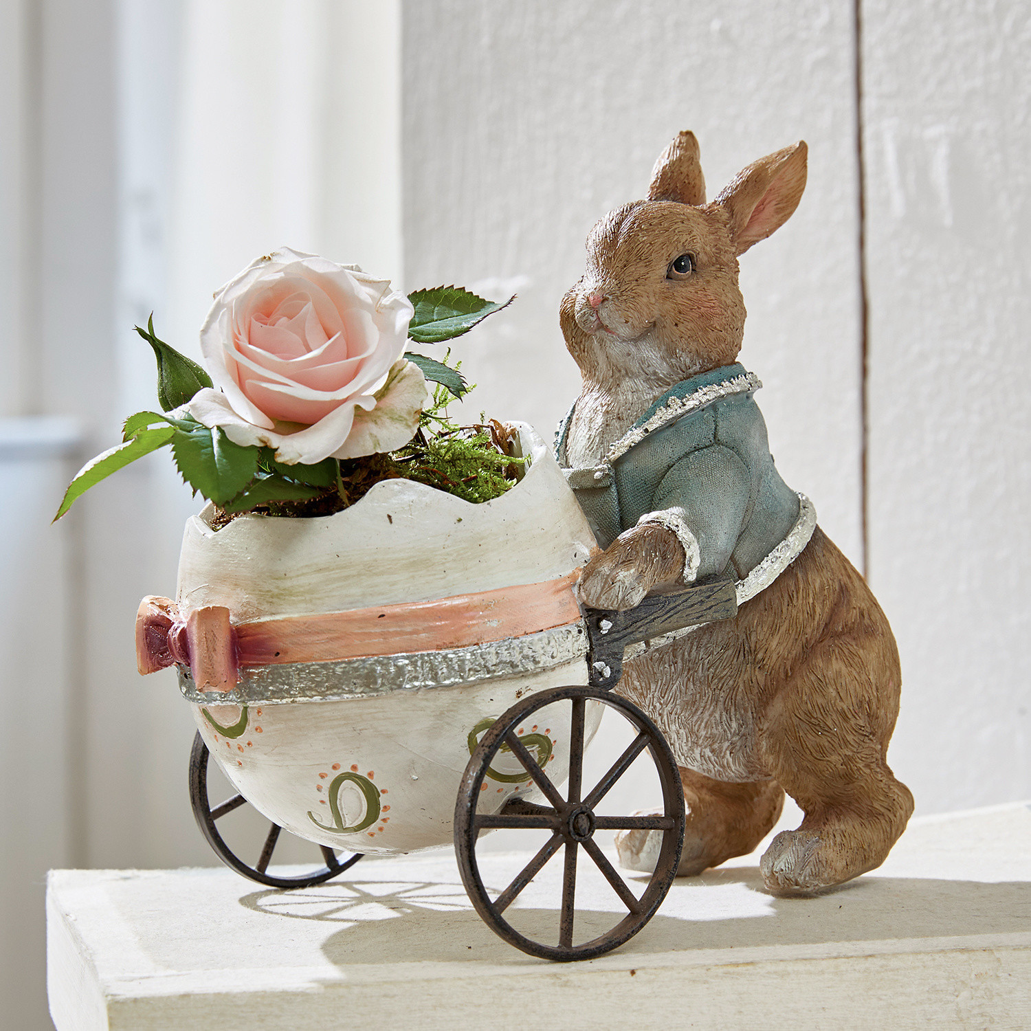 Hase Alençon Braune Hasenfigur aus Material schiebt weißen Wagen in Eiform mit rosa Rose