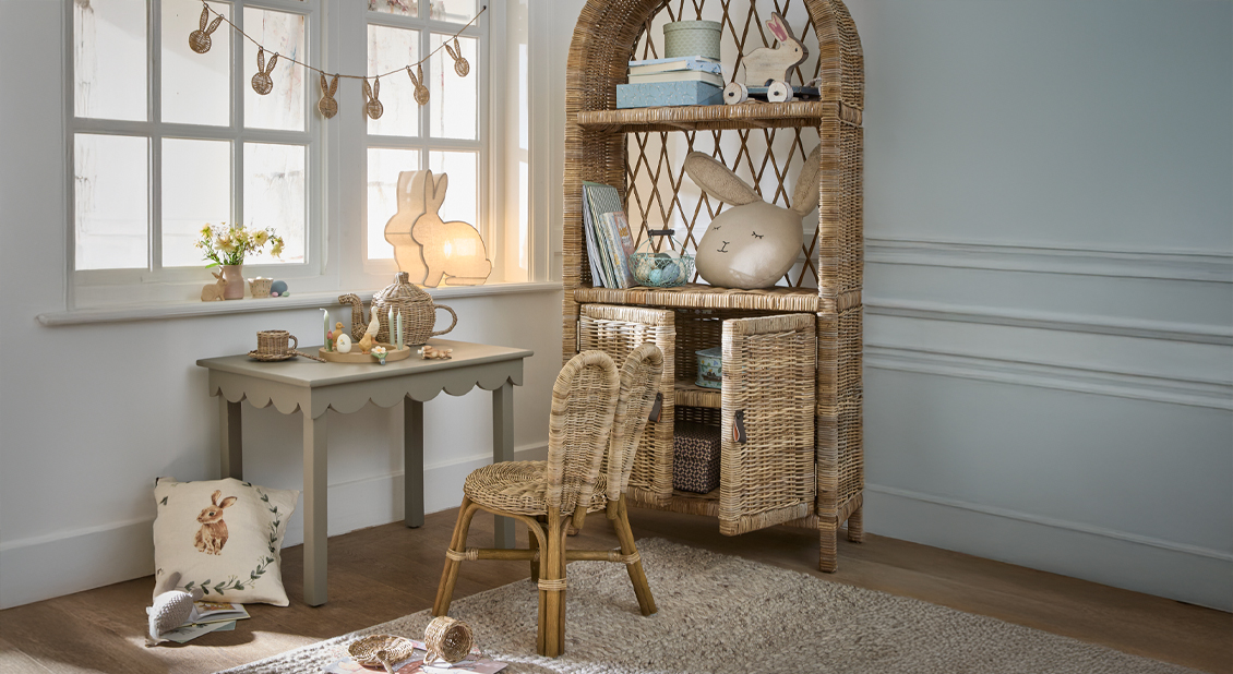 Gemütliche Kinderecke mit Rattanschrank, Stühlen und Hasen-Dekorationen in hellem Raum