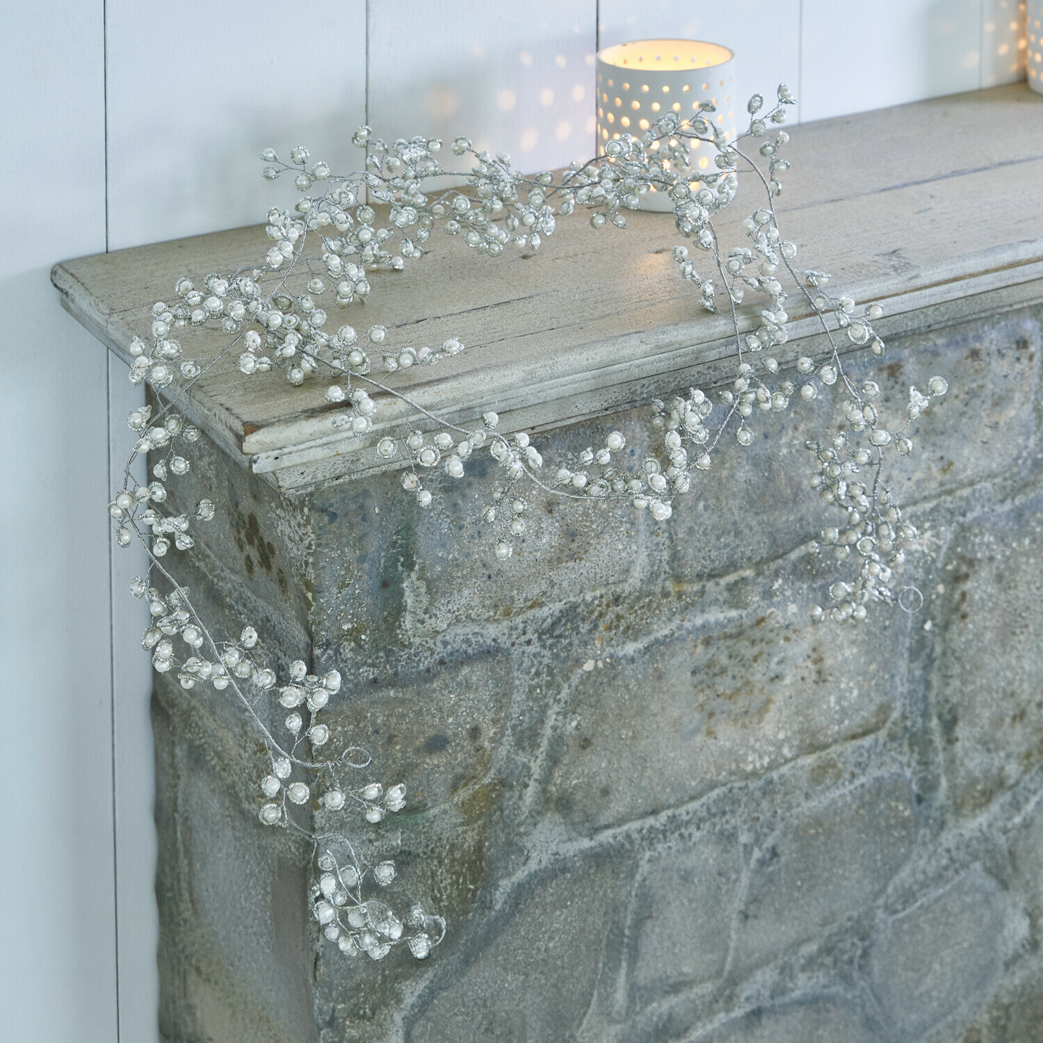 Zarter Dekokranz mit weißen Perlen auf silbernem Draht, ideal für Kamin oder Regal als Deko