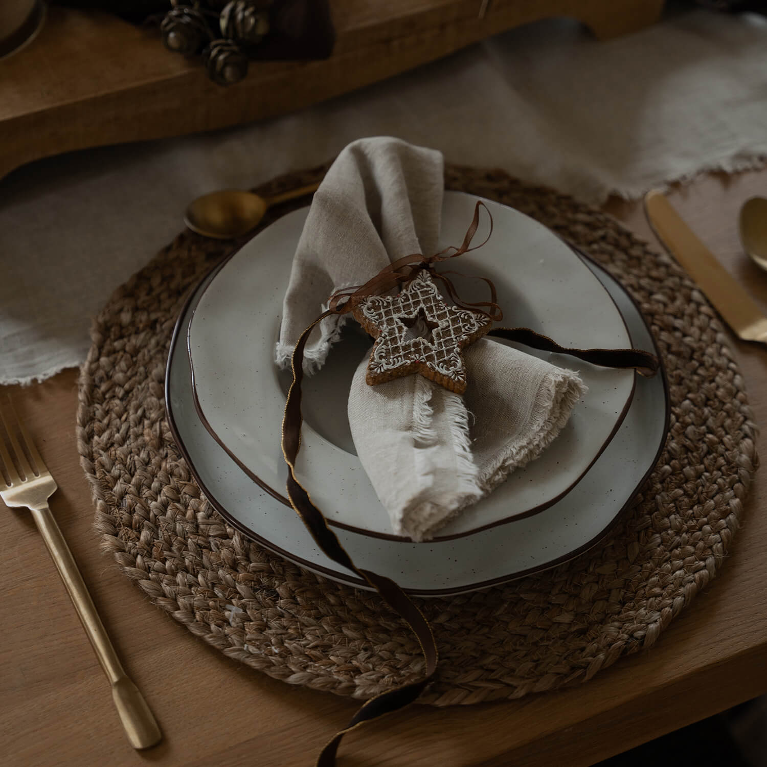 Rustikales Tischset mit Keramiktellern und Leinenserviette mit verzierten Lebkuchenstern