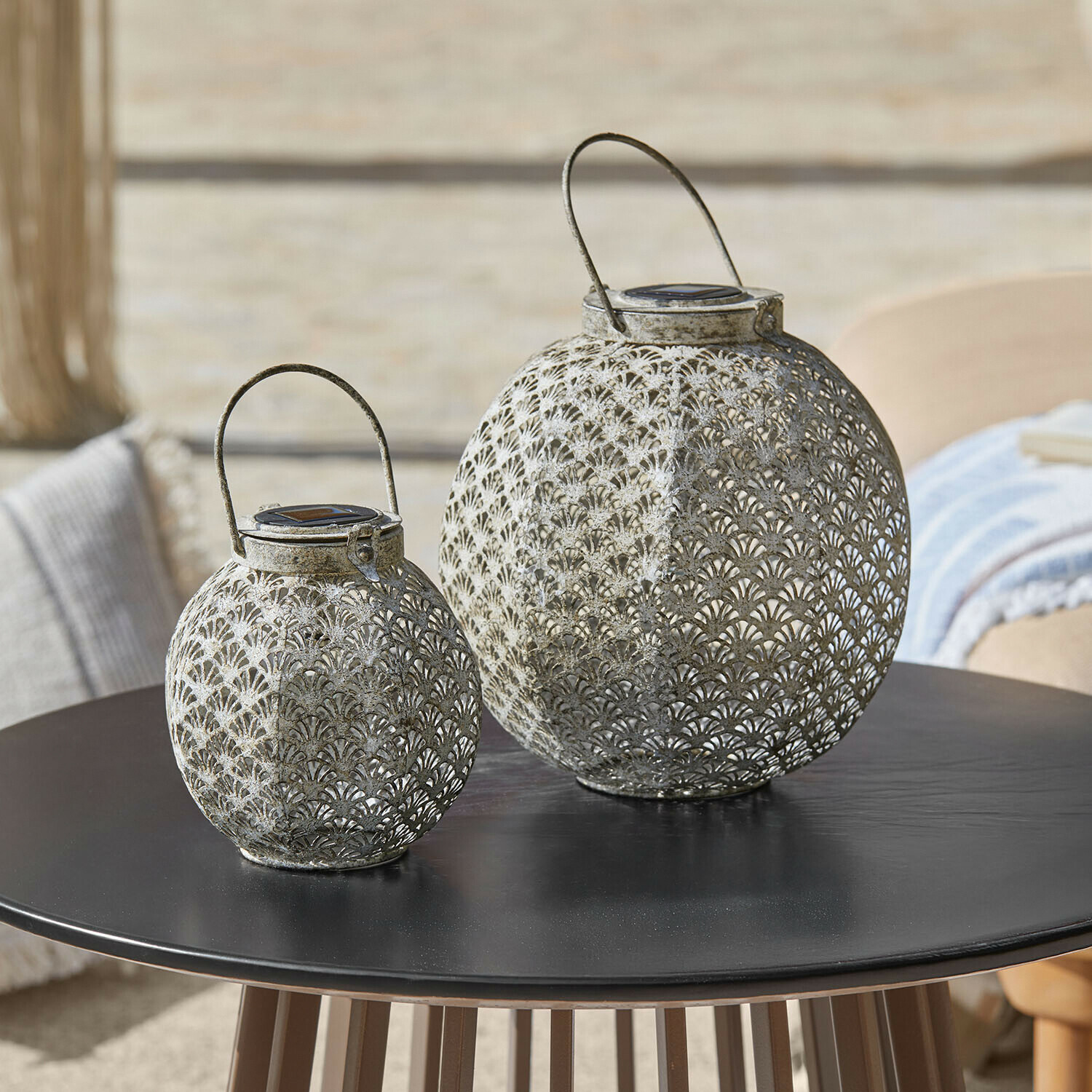 Zwei graue, filigrane Metalllaternen auf schwarzem Tisch, dekorative Outdoor-Beleuchtung