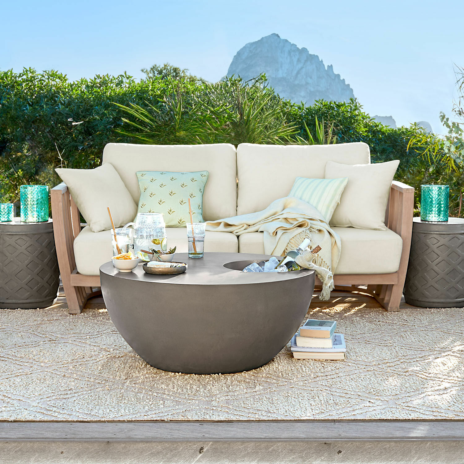 Sofa FSC®-100% Vézère Moderner runder Gartentisch aus grauem Beton auf Terrasse mit beigem Sofa und Kissen