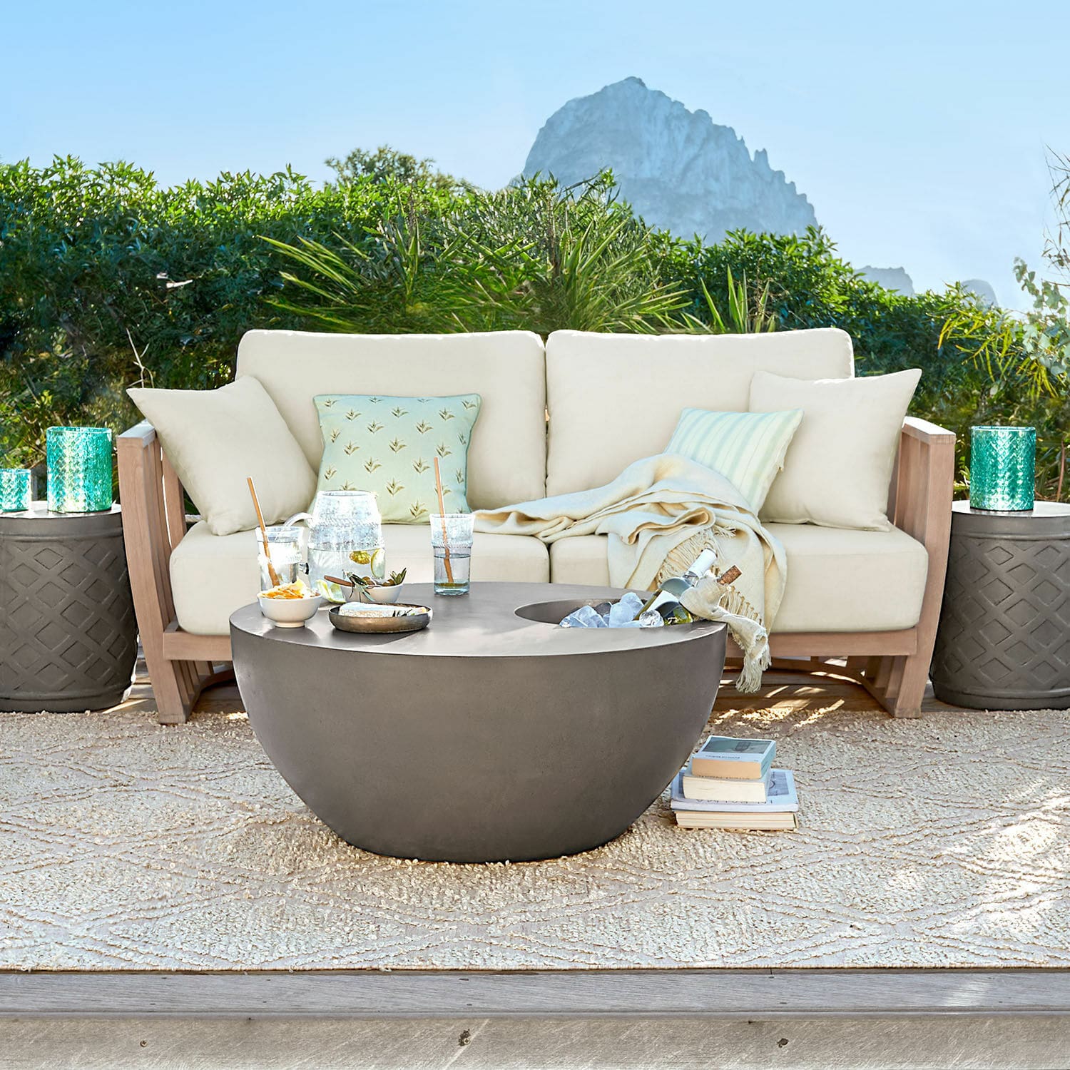 Sofa FSC®-100% Vézère Moderner runder Gartentisch aus grauem Beton auf Terrasse mit beigem Sofa und Kissen