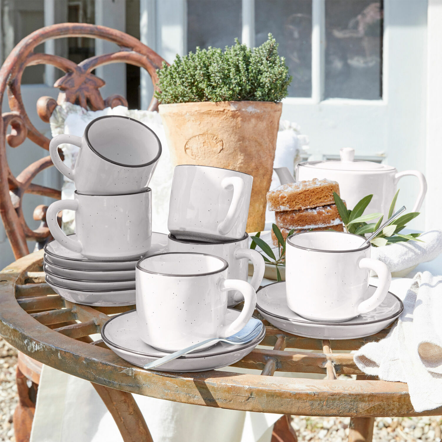Tasse mit Untertasse 6er Set Biarré Set aus weißen Keramiktassen mit Untertassen auf rustikalem Gartentisch mit Kuchen und Blumentopf