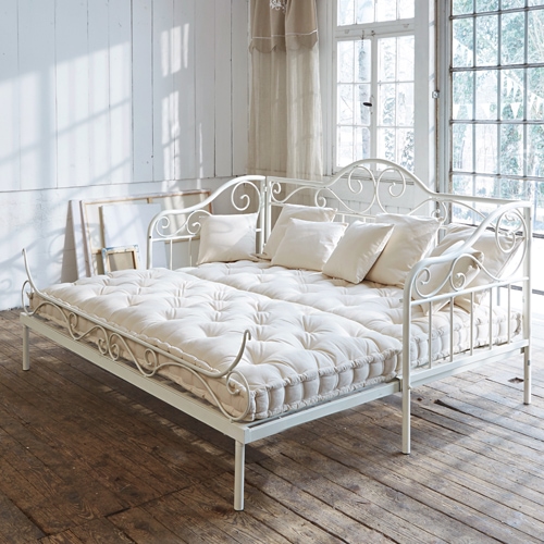 Weiße Metallsofa mit cremefarbenem Matratze und Kissen in hellem Raum mit Holzboden