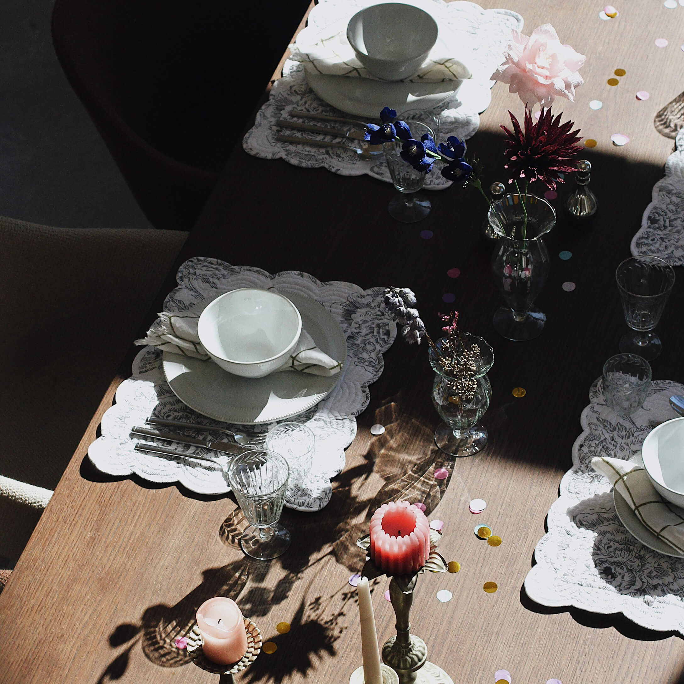 Eleganter gedeckter Tisch mit weißem Porzellan, Gläsern und Kerzen auf Holzplatte