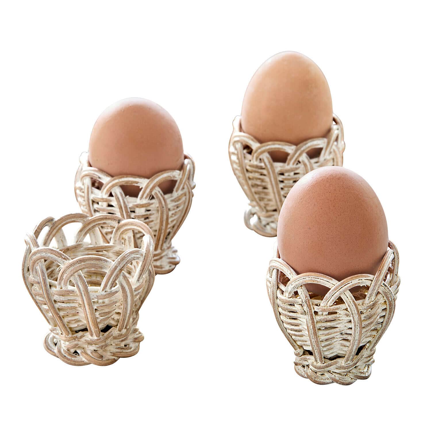 Set aus weißen Rattan-Eierhaltern mit braunen Natur-Eiern für ein rustikales Frühstück