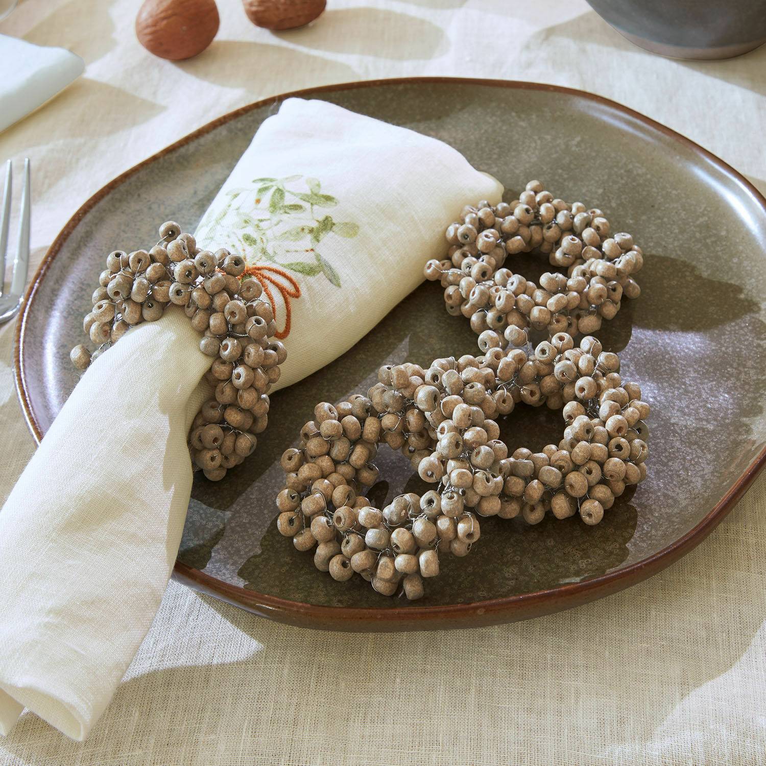 Serviettenring 4er Set Costavio Natürliche beige Holz-Serviettenringe auf einem Keramikteller zur Tischdekoration