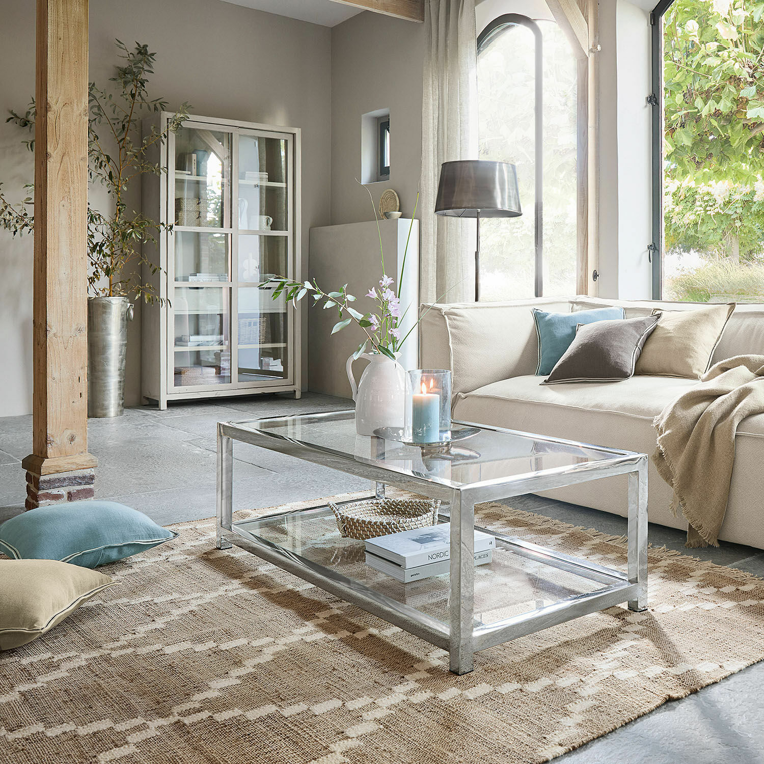 In- & Outdoorteppich Piera Moderner Glastisch mit Metallrahmen im hellen Wohnzimmer mit beigem Sofa und Dekorationen