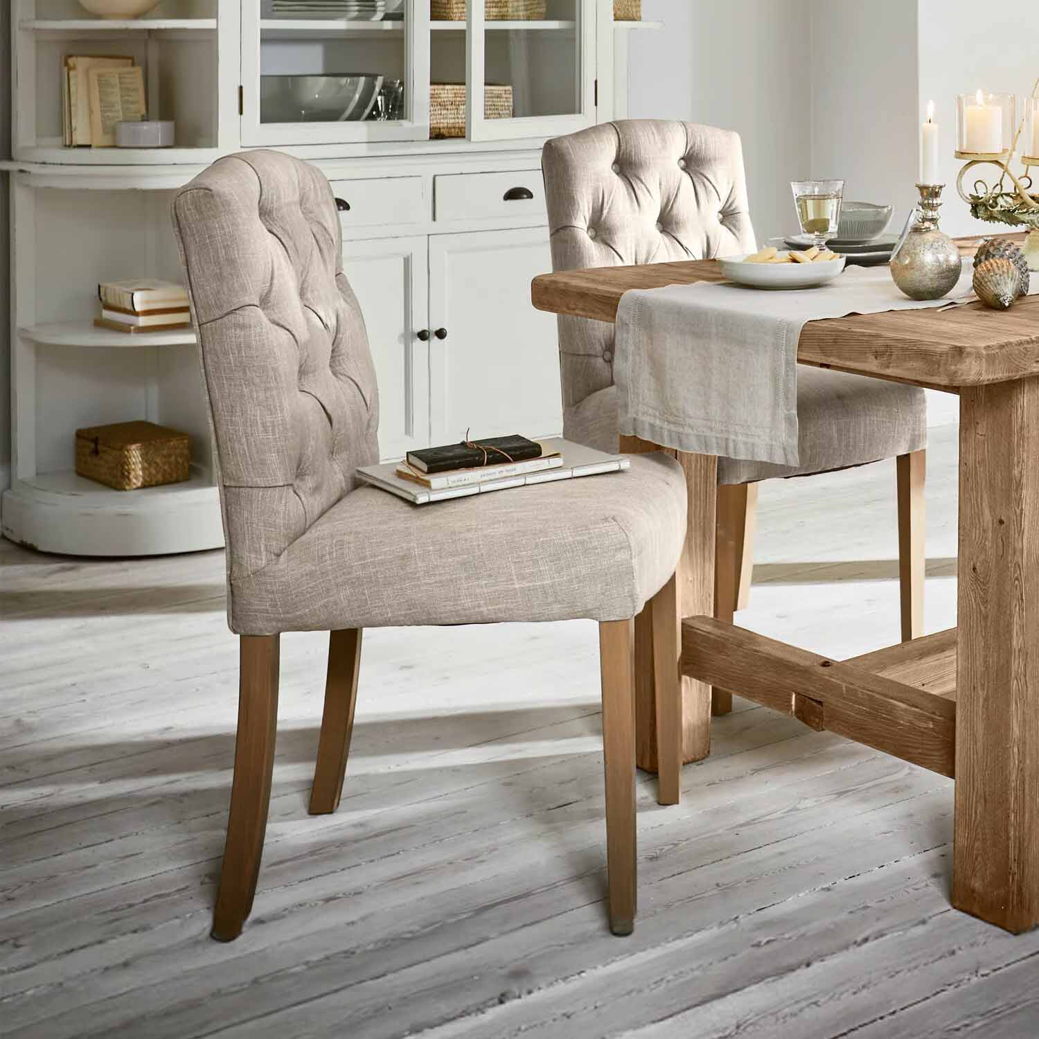Beiger gepolsterter Stuhl mit Holzbeinen an einem Holztisch in hellem Esszimmer