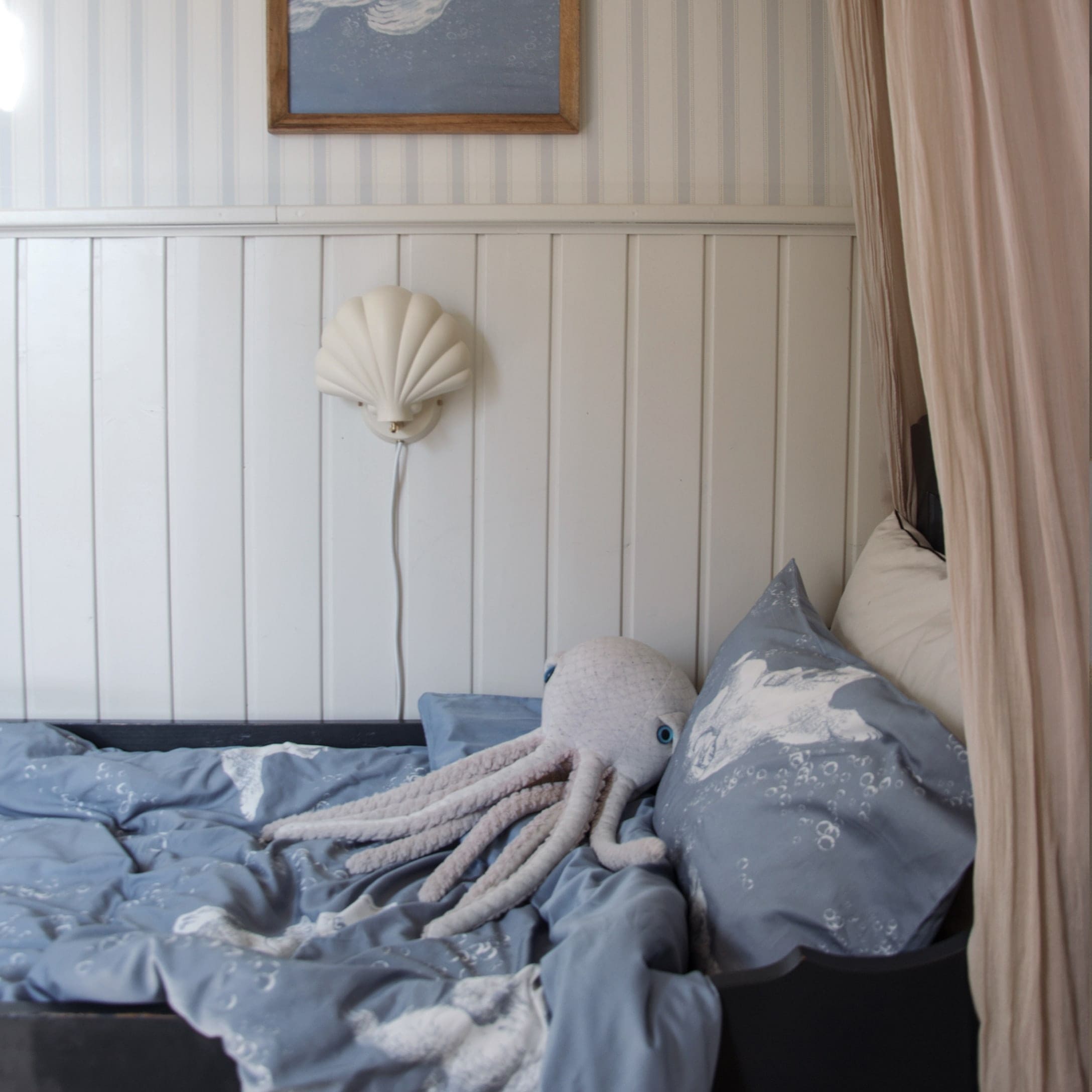 Blaue Kinderbettwäsche mit Oktopus-Motiv und Plüsch-Oktopus auf einem Bett im Kinderzimmer
