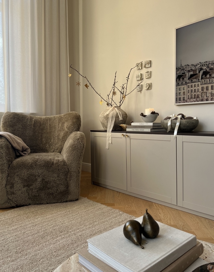 Kuschelige Winterecke mit weichem Sessel und natürlichen Dekorationen auf hellem Sideboard