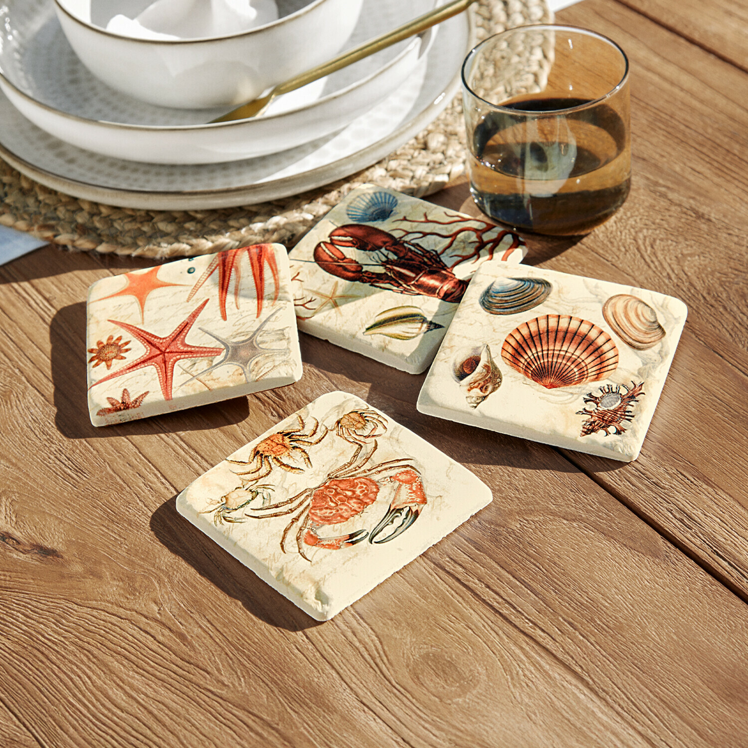Vier keramische Untersetzer mit maritimen Motiven in warmen Farben auf Holztisch