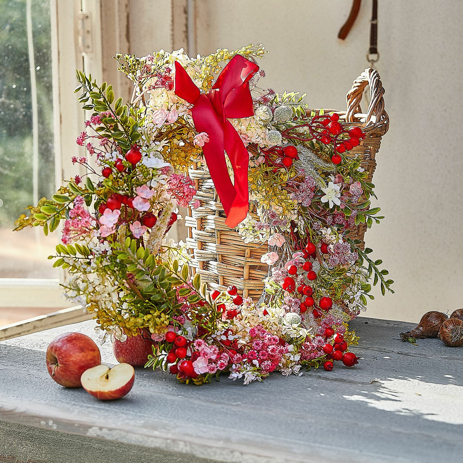 Kranz Selivane Dekorativer Kranz mit roten Beeren und rosa Blüten auf einem Weidenkorb auf dem Tisch