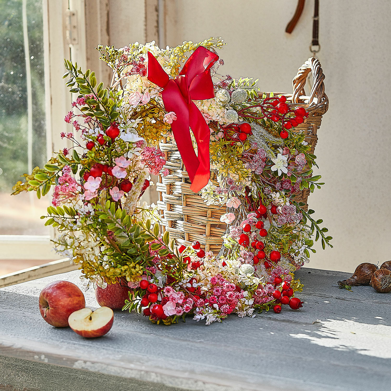 Kranz Selivane Dekorativer Kranz mit roten Beeren und rosa Blüten auf einem Weidenkorb auf dem Tisch