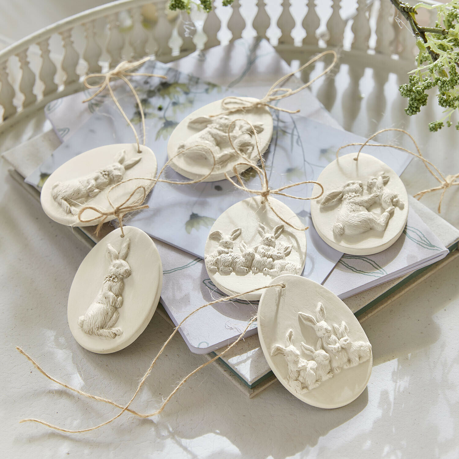 Ostereier aus weißem Ton mit Hasenreliefs und Juteschnur zum Aufhängen, festliche Dekoration