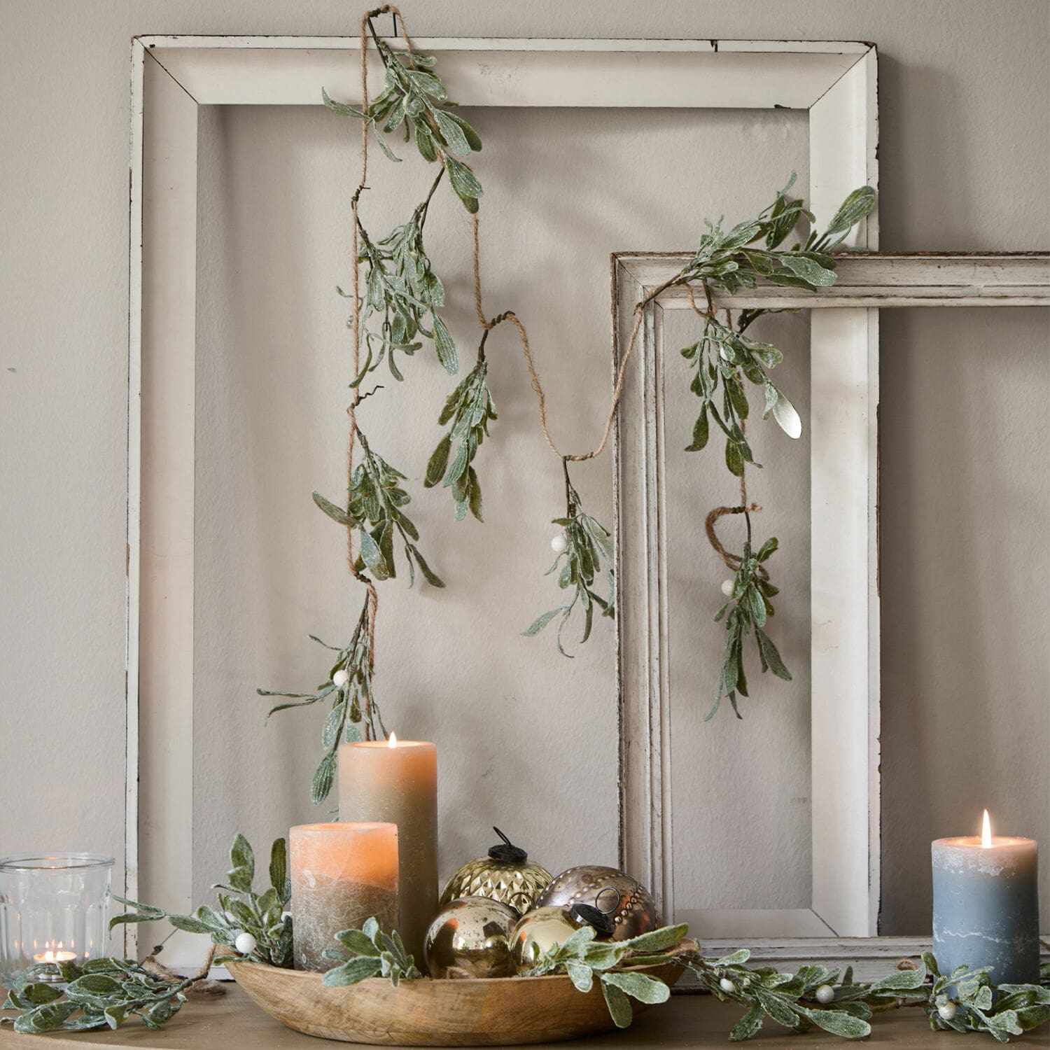 Girlande Mistletoe Dekorative Girlande mit grünen Blättern und weißen Beeren vor weißen Holzrahmen, Kerzen und Deko