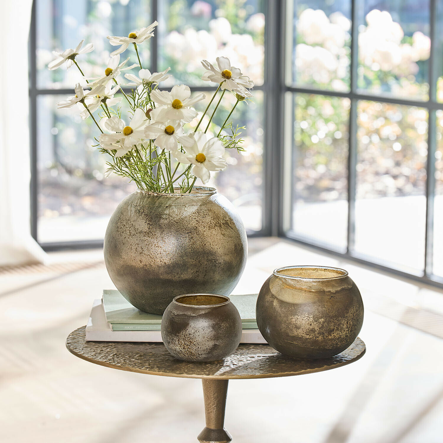 Set aus drei runden Glasvasen in antikgold auf Tisch mit Blumen und Büchern dekoriert