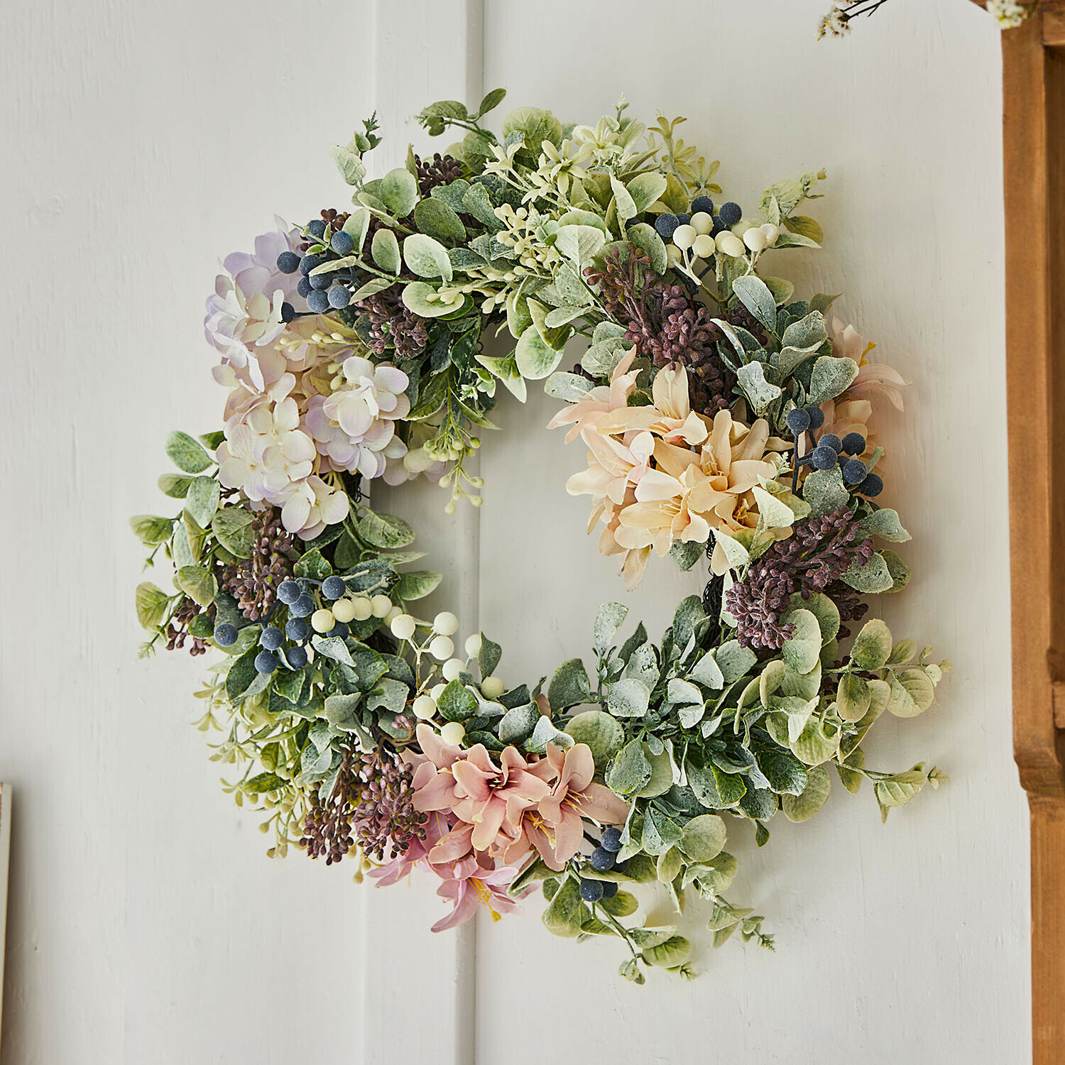 Dekorativer Kranz mit grünen Blättern und pastellfarbenen Blumen als Frühlingsdeko