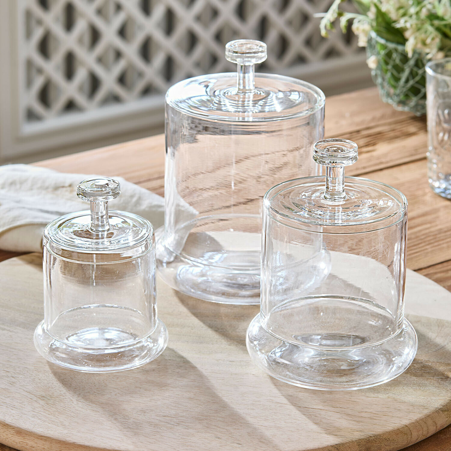 Set aus drei transparenten Glasbehältern mit Deckeln auf Holzbrett zur Aufbewahrung