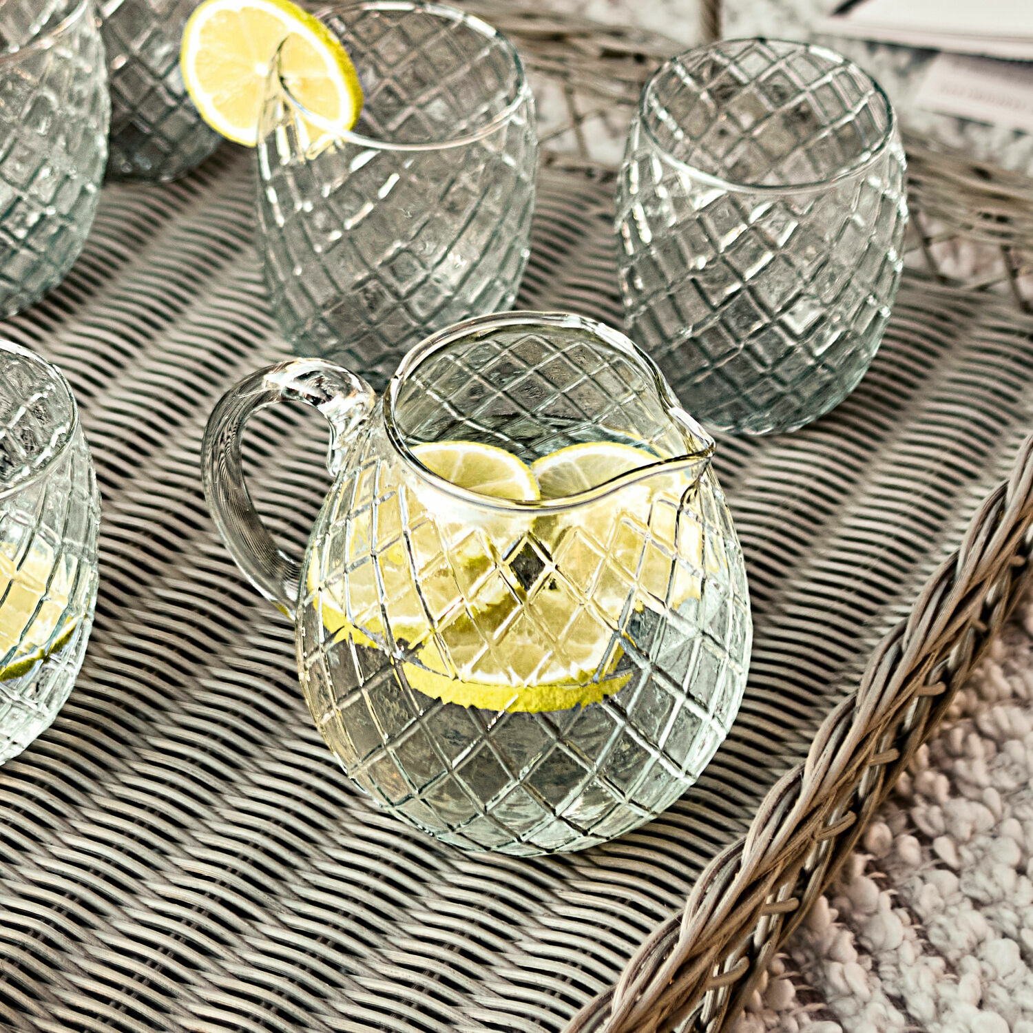 Glaskrug und Gläser mit Rautenmuster auf Tablett mit Zitronenscheiben, ideal für Getränke.
