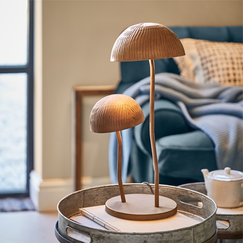 Holz-Tischlampe in Pilzform in Naturfarbe auf Metalltablett im Wohnzimmer
