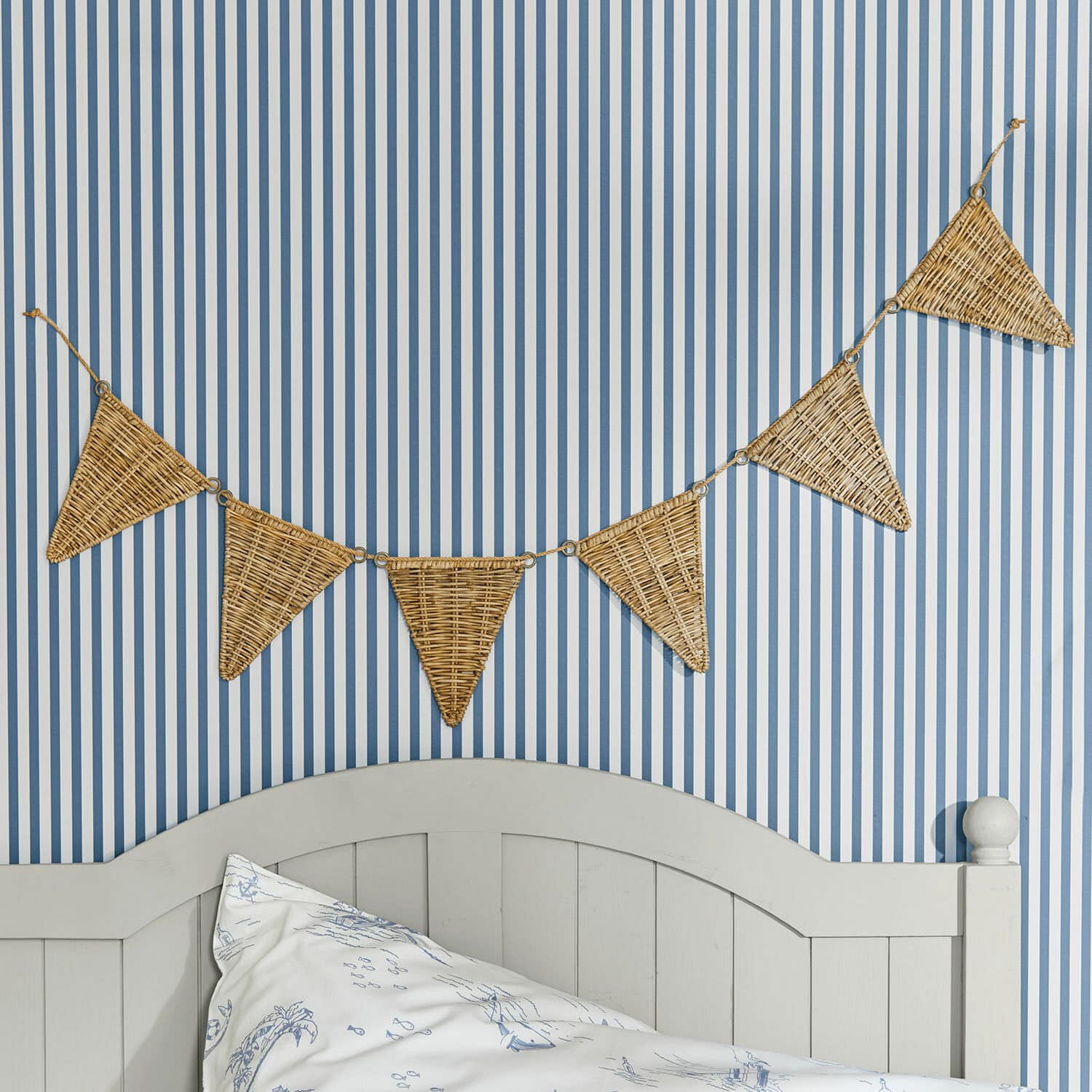 Wimpelgirlande Anglemont Dekorative Wimpelkette aus geflochtenem Rattan an blau-weiß gestreifter Wand im Schlafzimmer