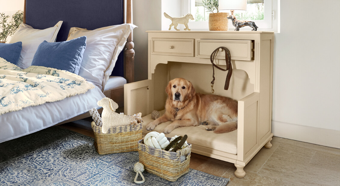 Beiger Holzschrank mit Hundebett und Polster, neben Bett mit blauen Kissen in Schlafzimmer