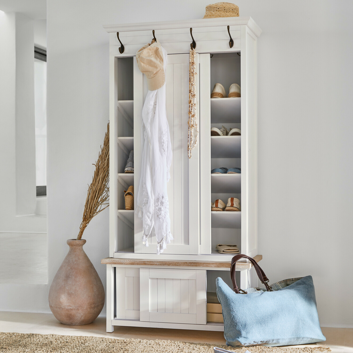 Garderobe Remerton Weiße Holzschuhschrank mit Haken und Regalen, blaue Tasche und Strohhut als Dekor