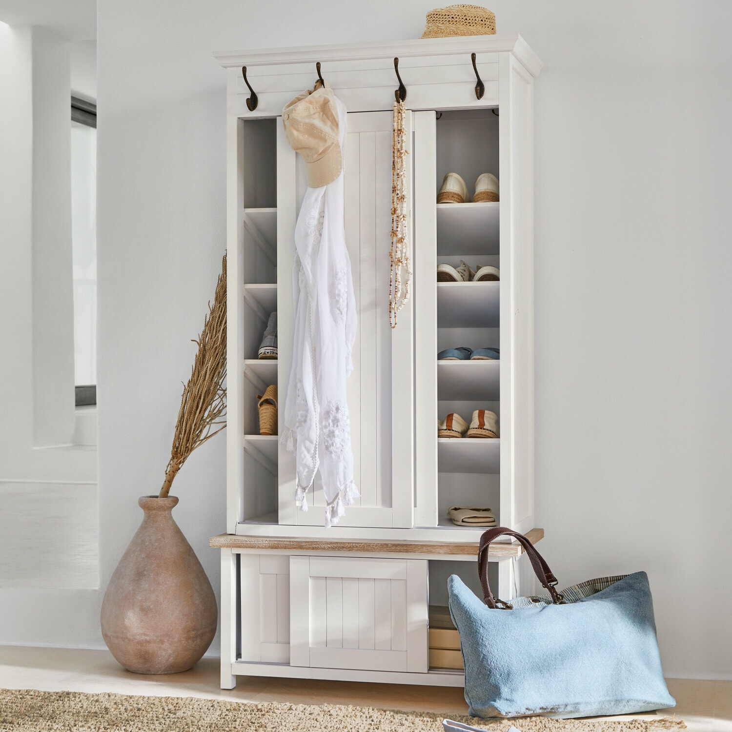 Garderobe Remerton Weiße Holzschuhschrank mit Haken und Regalen, blaue Tasche und Strohhut als Dekor