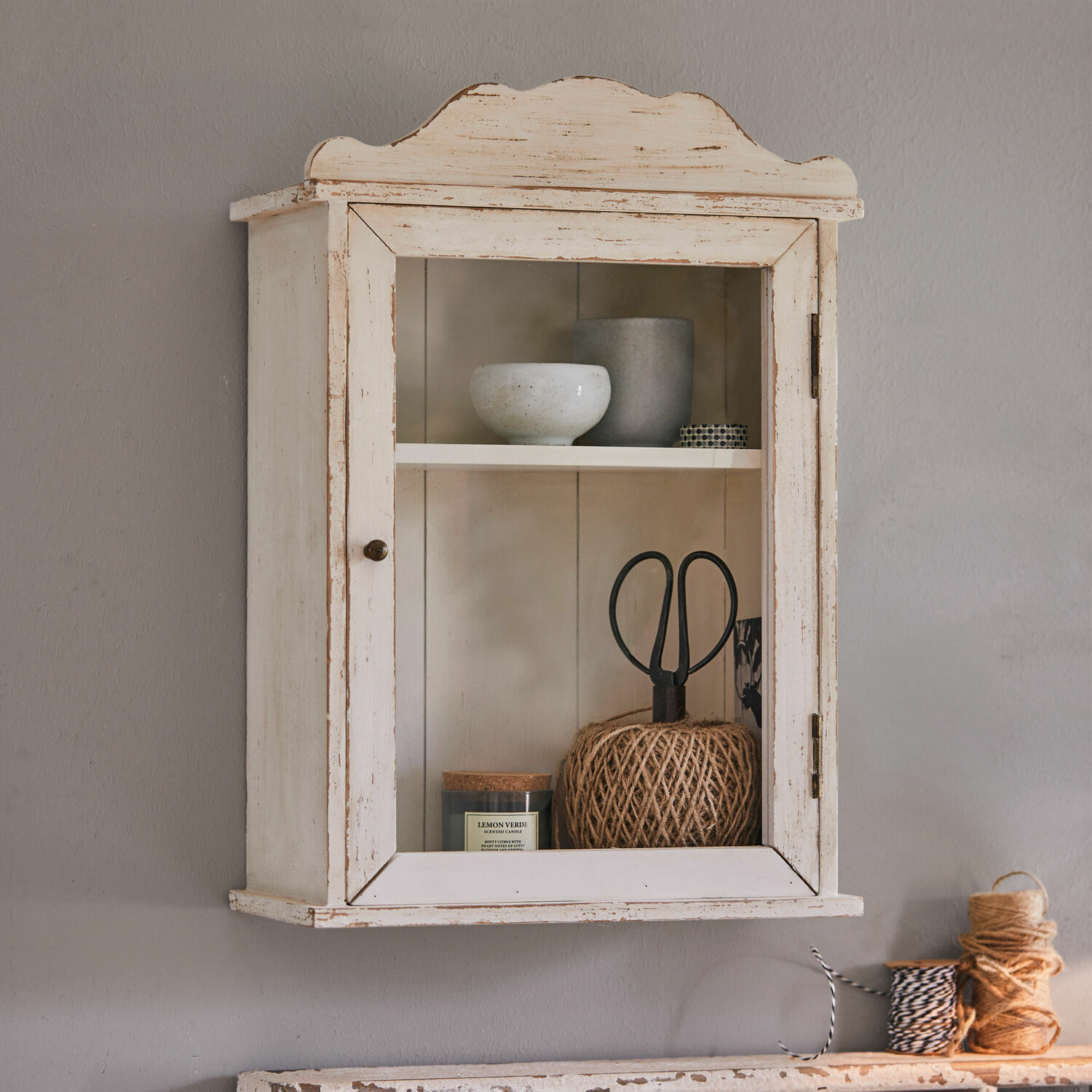 Wandschrank Sandrine Hängeschrank aus Holz im Vintage-Stil in Weiß mit Glastür und dekorativen Gegenständen innen