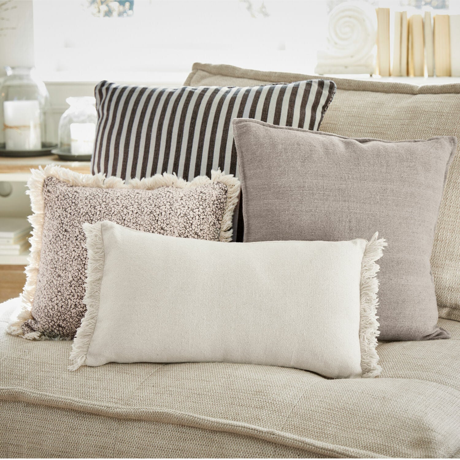Kissen 4er Set Valenciennes Vier dekorative Kissen in neutralen Farben auf einem beigen Sofa für das Wohnzimmer