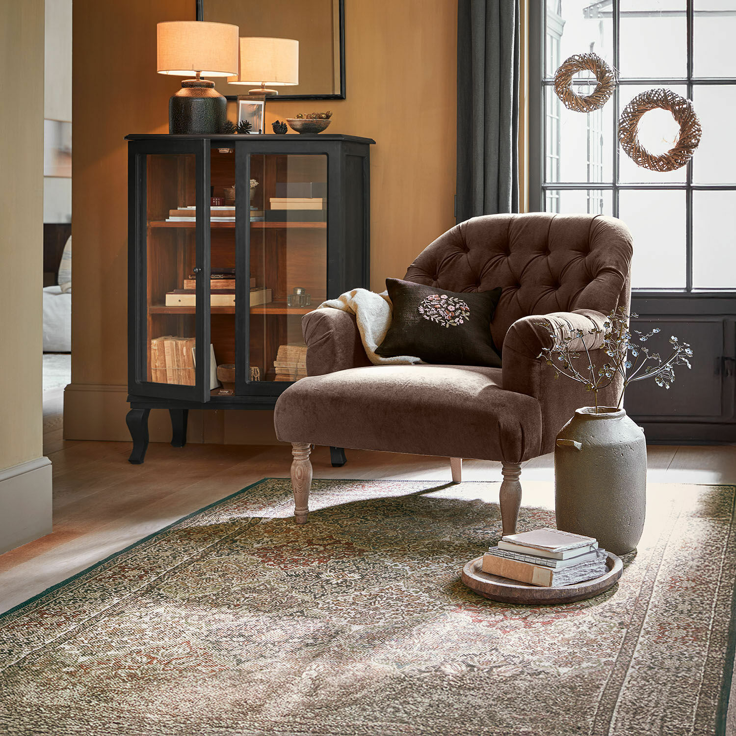 Brauner Samtfotel mit gesteppter Rückenlehne und Holzbeinen in gemütlichem Wohnzimmer mit Teppich