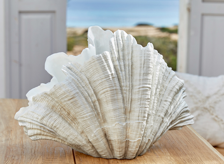 Weiße Muschel-Dekoration aus Kunstmaterial auf Holztisch im maritimen Wohnstil